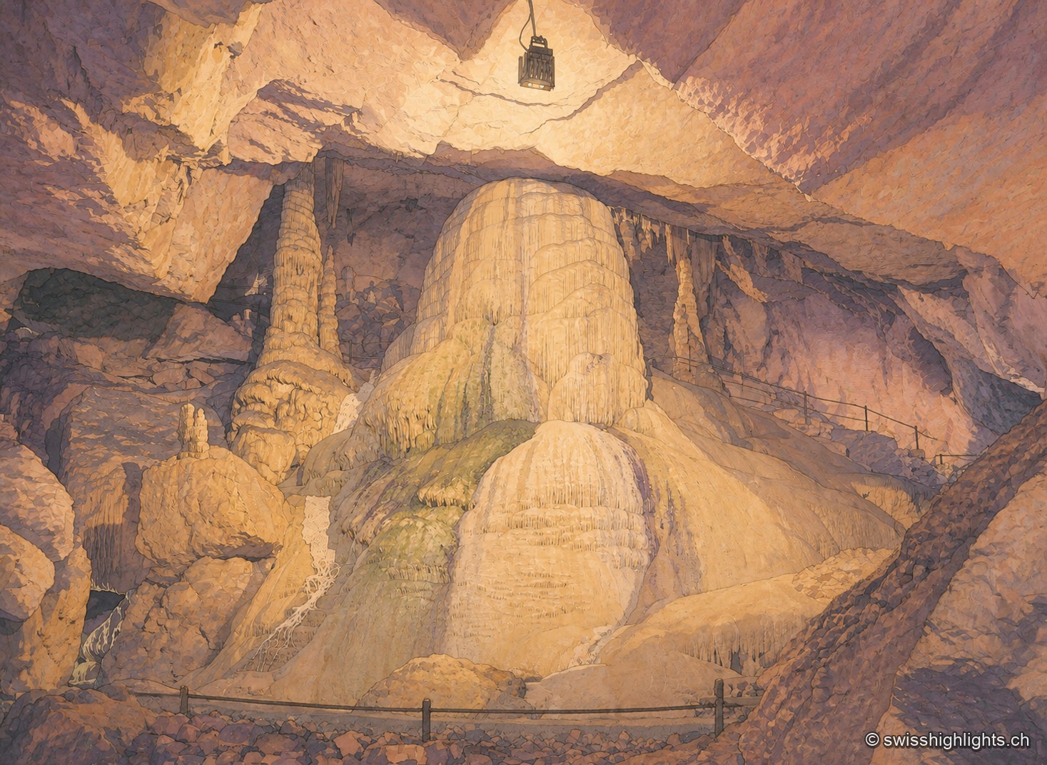 Dans une vaste salle souterraine, un imposant massif de calcite aux teintes ocre et mauves s'élève du sol jusqu'à toucher la voûte, sous un éclairage artificiel qui alterne tons chauds et reflets bleutés ; une rambarde de sécurité borde le passage au premier plan.