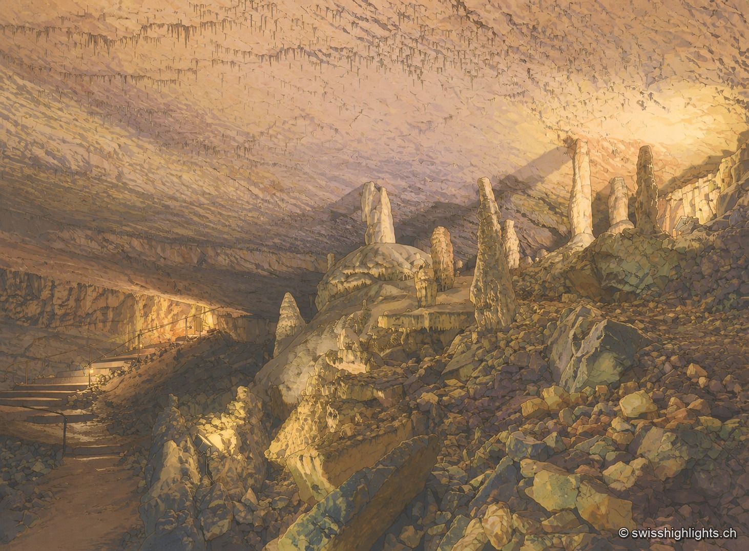 Une galerie de la grotte, où des colonnes de calcite blanchâtre se dressent parmi des blocs rocheux épars, sous un éclairage chaud qui souligne le relief du sol et des concrétions.