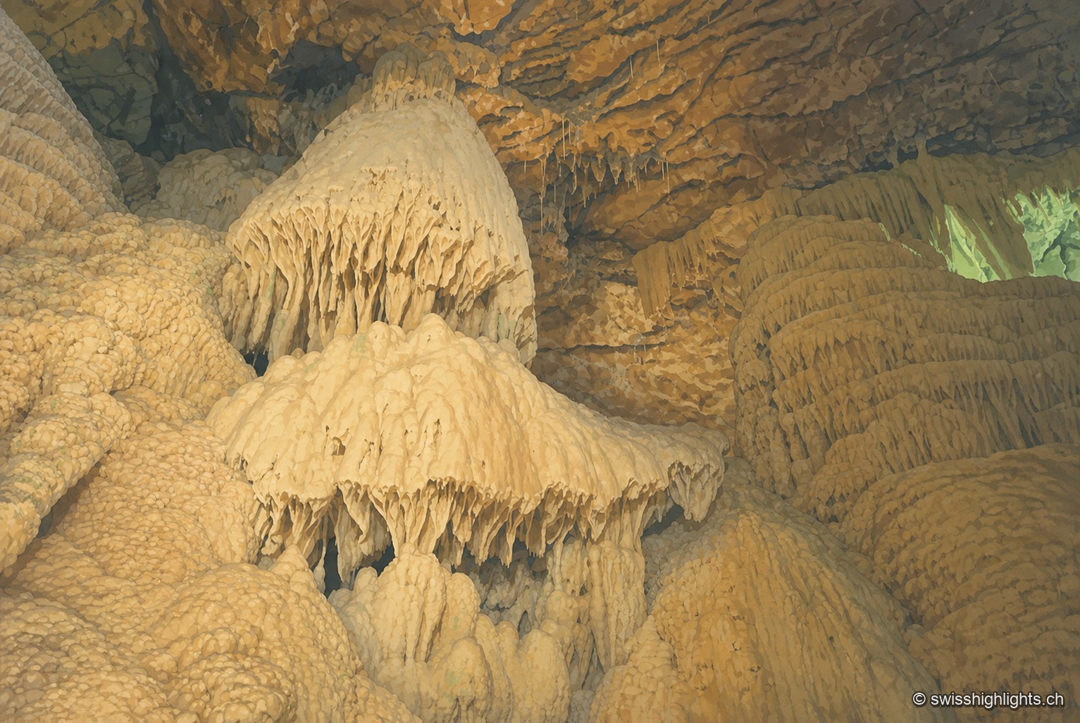 Une large draperie de calcite, aux formes arrondies évoquant des méduses suspendues, recouvre la paroi d'une salle souterraine baignée d'une lumière ocre chaude.