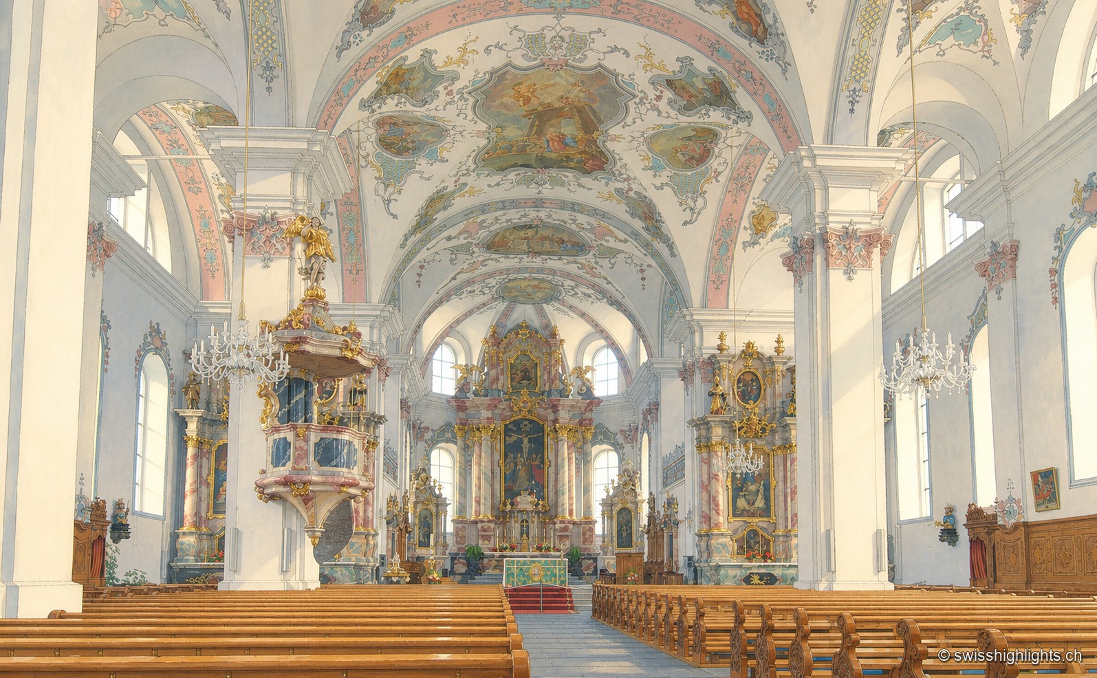 Intérieur de la nef de l'église Saint-Pierre-et-Paul : rangées de bancs, colonnes blanches, voûtes ornées et lustres s'alignent dans un axe central vers la chaire et l'autel, baignés d'une lumière pastel.